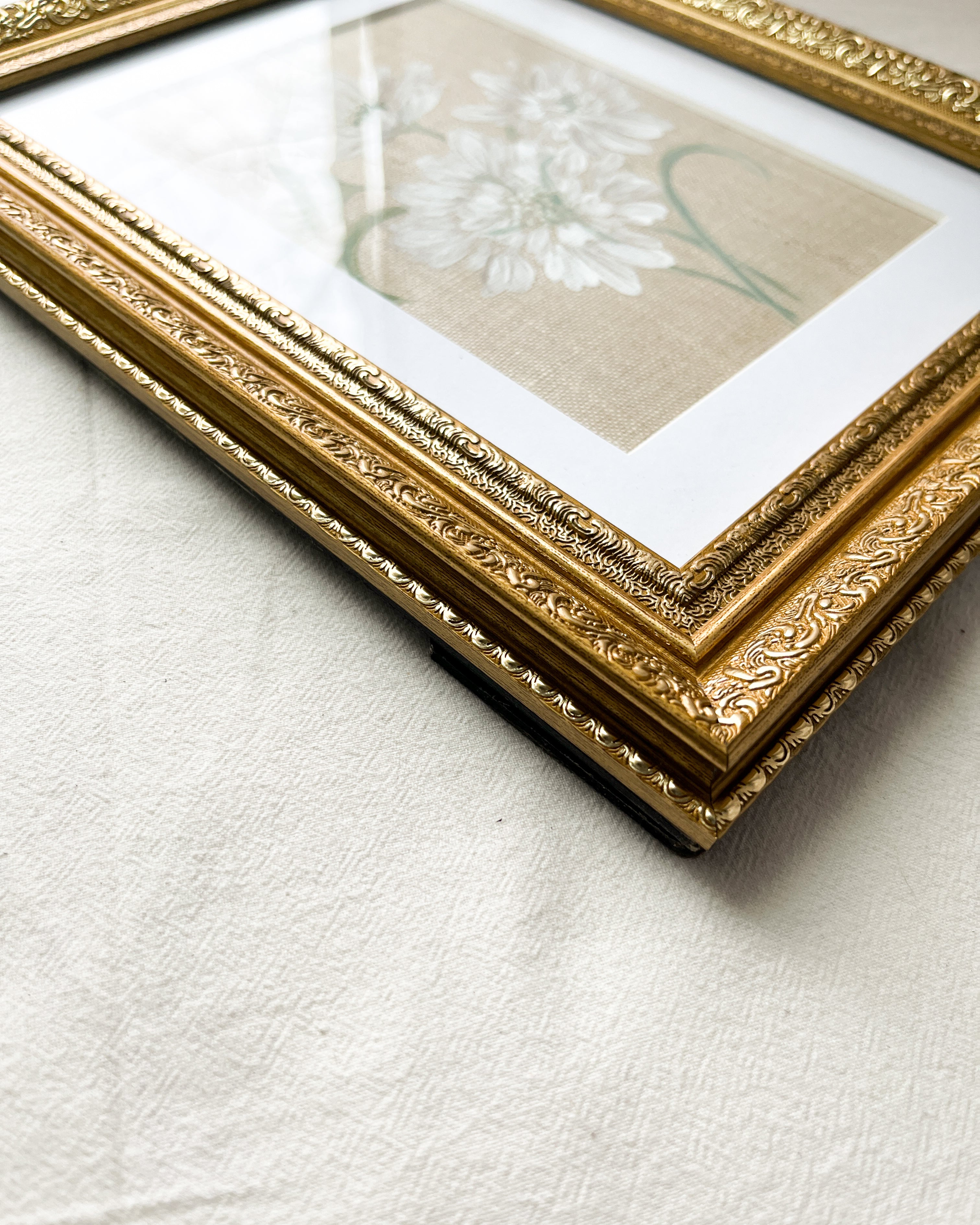 Close-up of ornate frame with elegant metallic finish on Reflective Bloom white scabiosa watercolor painting by Trisha Patel, botanical art wall décor.