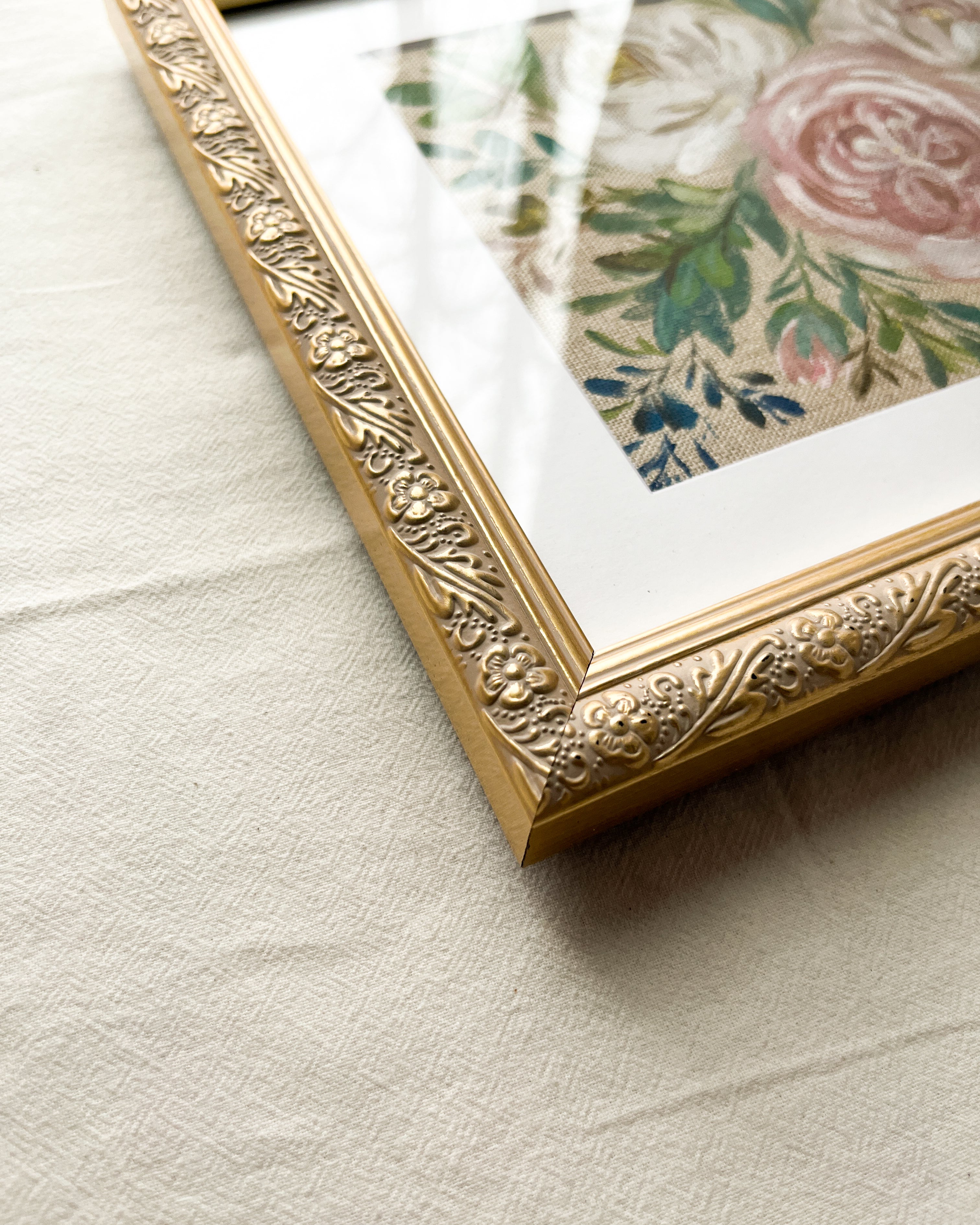 Close-up of subtly distressed champagne gold-tone metal frame with delicate embossed floral detailing on Rooted in Grace rose watercolor painting by Trisha Patel, botanical art