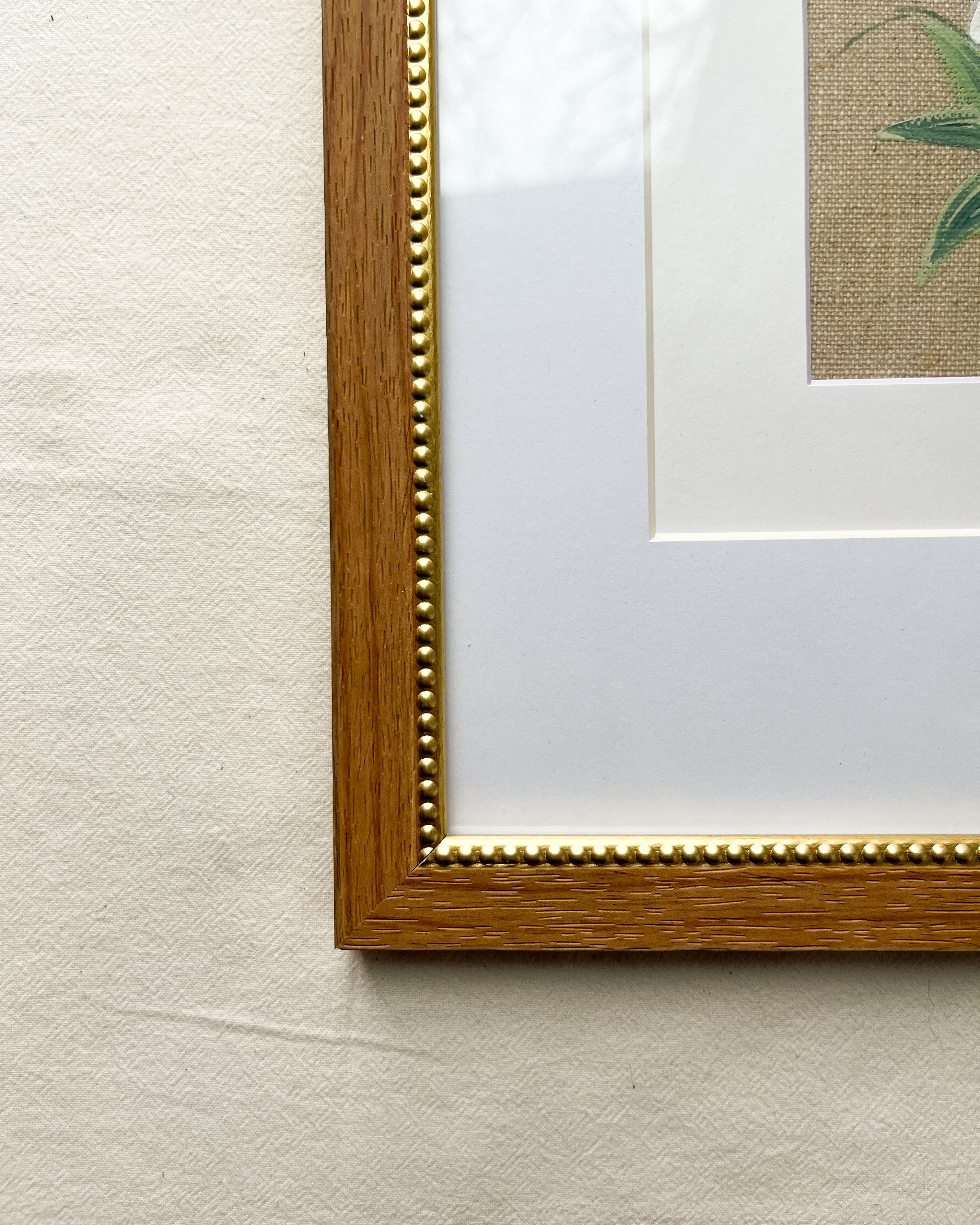 Close-up of warm-toned natural wood frame with gold beaded inner trim on Unfolding Grace peony watercolor painting by Trisha Patel, botanical wall art