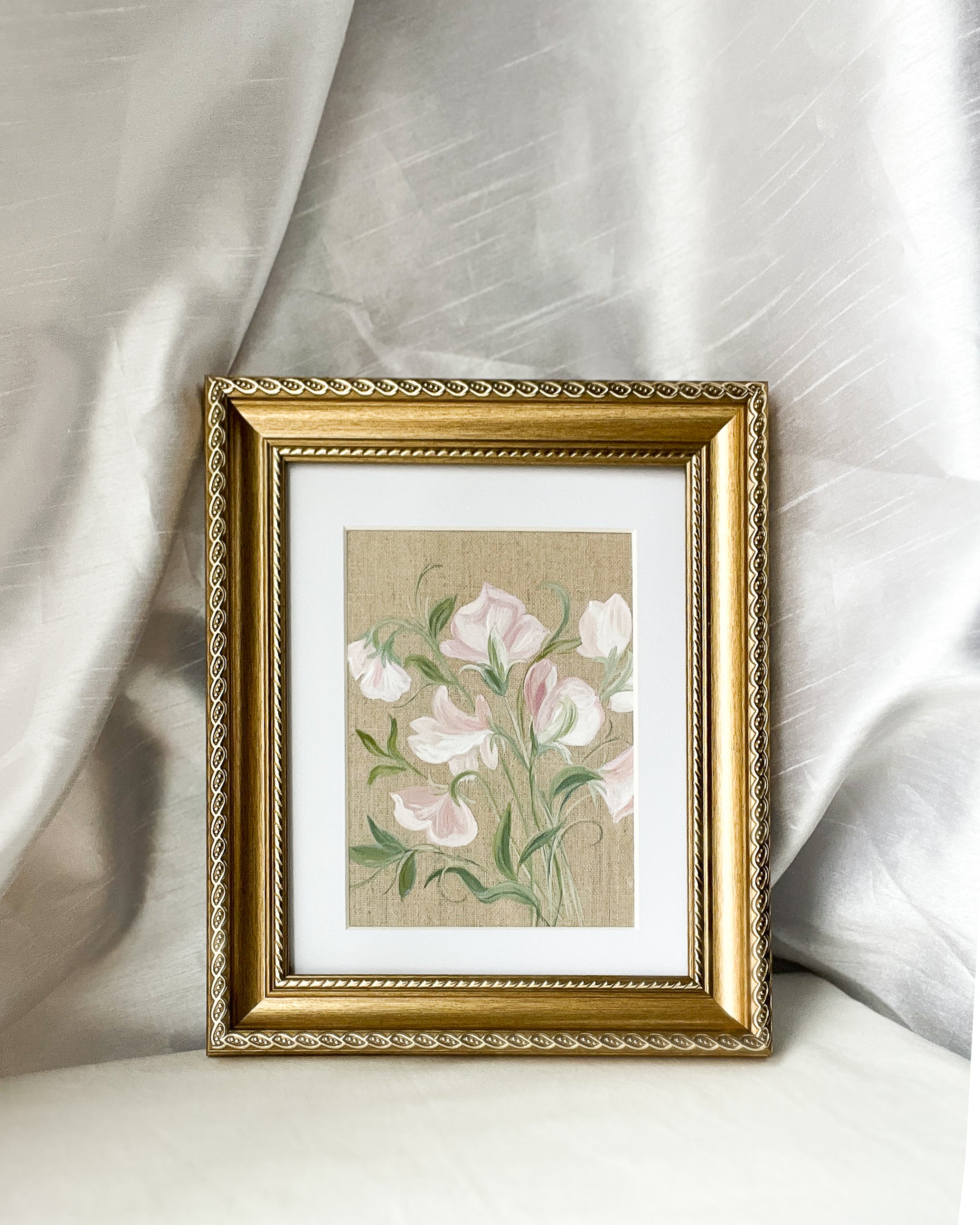 Sweet pea botanical watercolor art by Trisha Patel displayed in elegant gold-toned wooden frame with vintage rope-inspired border, symbolizing gratitude and the gentle power of love in home décor.