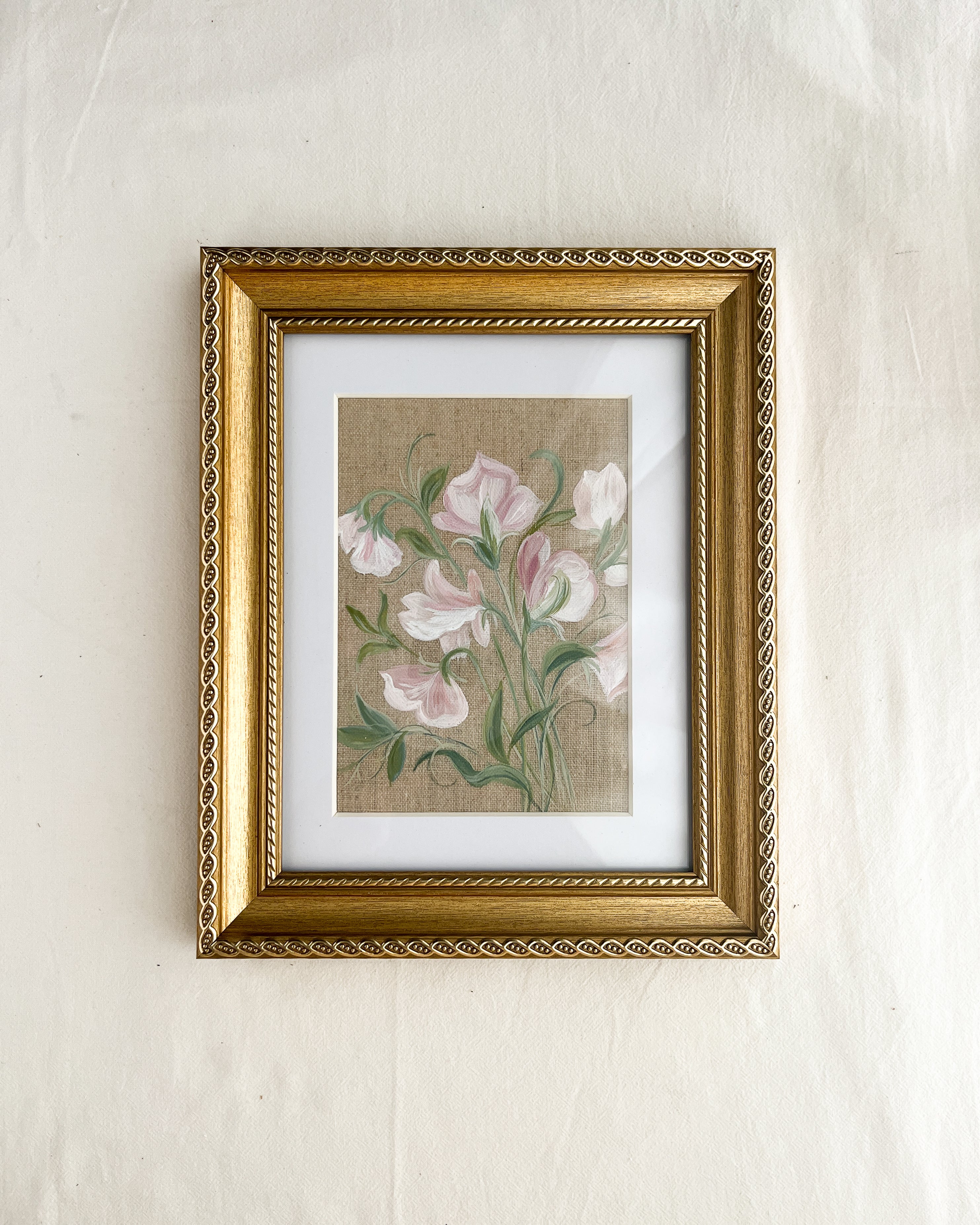 Sweet pea botanical watercolor art by Trisha Patel displayed in elegant gold-toned wooden frame with vintage rope-inspired border, symbolizing gratitude and the gentle power of love in home décor