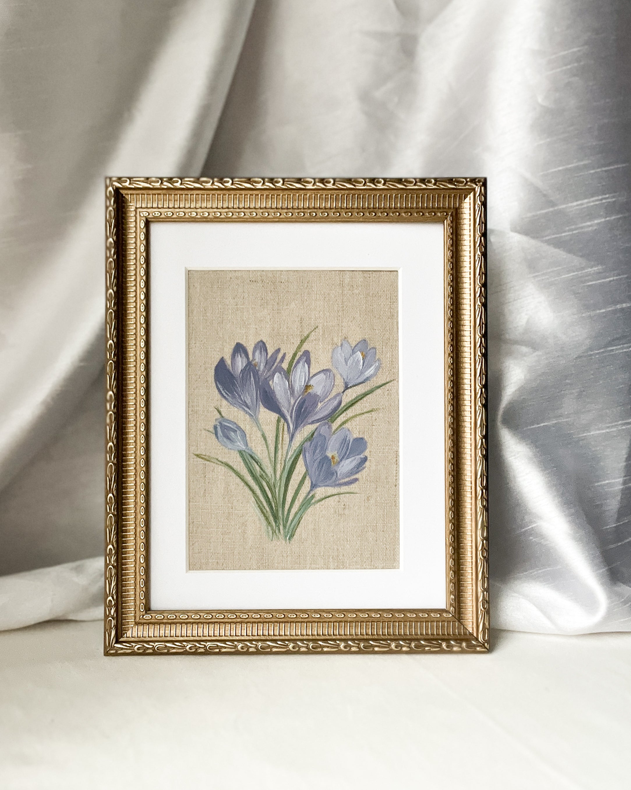 'Springs Promise' crocus botanical watercolor art by Trisha Patel displayed in elegant gold-toned wooden frame with vintage-inspired beaded and floral embossed border.