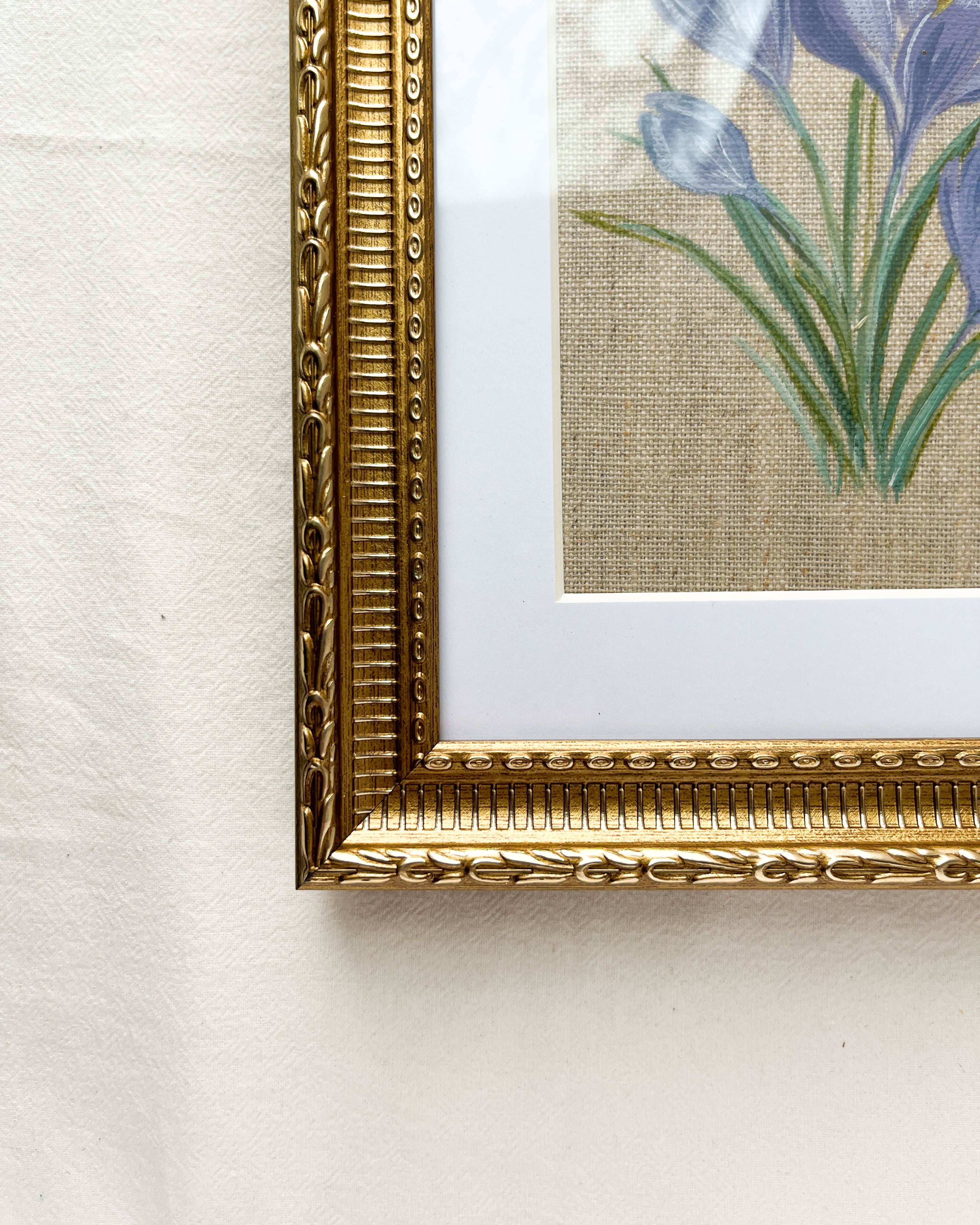 Detailed close-up of embossed floral and beaded pattern on gold-toned wooden frame of Springs Promise crocus watercolor painting by Trisha Patel