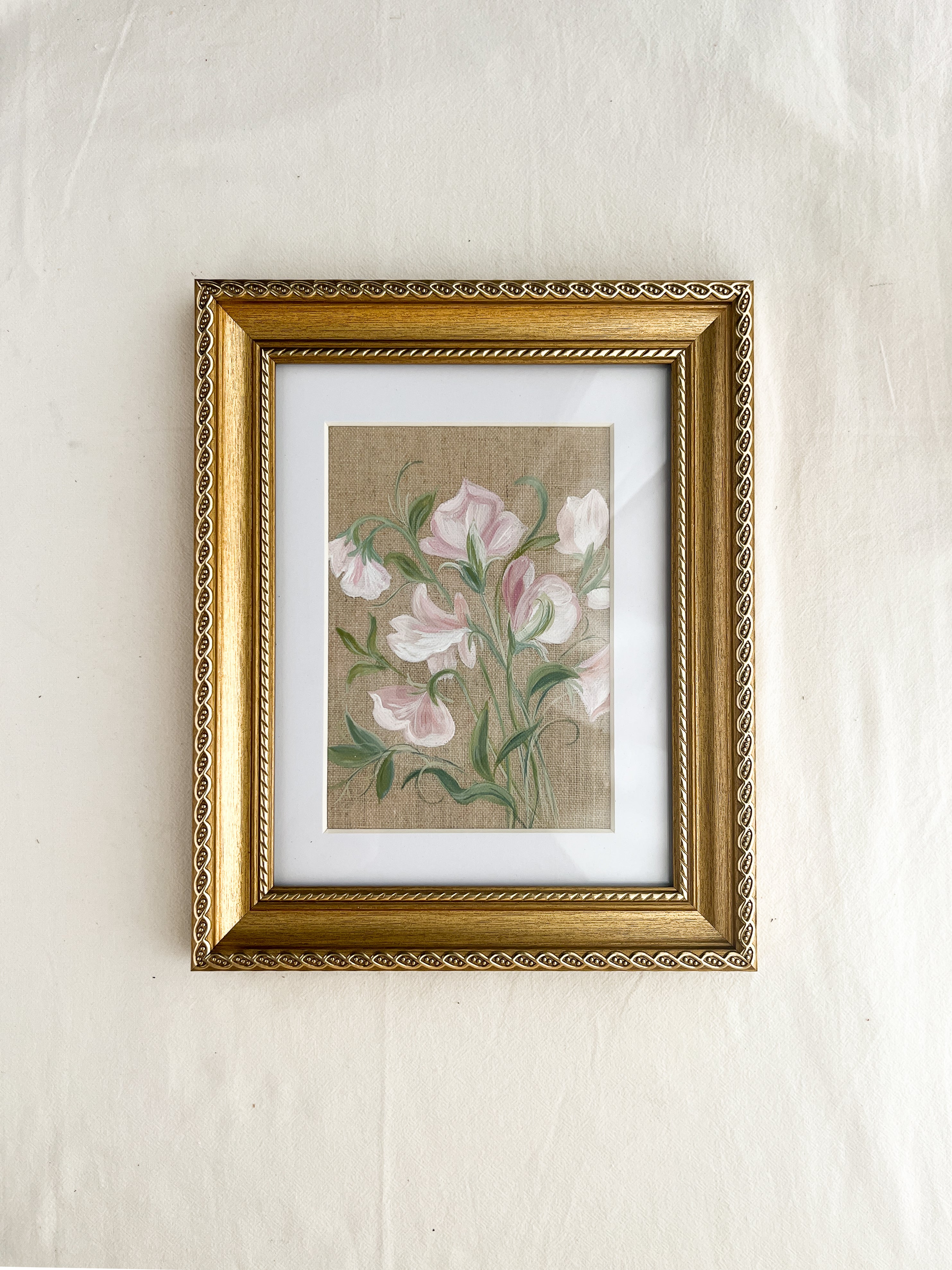 Sweet pea botanical watercolor art by Trisha Patel displayed in elegant gold-toned wooden frame with vintage rope-inspired border, symbolizing gratitude and the gentle power of love in home décor
